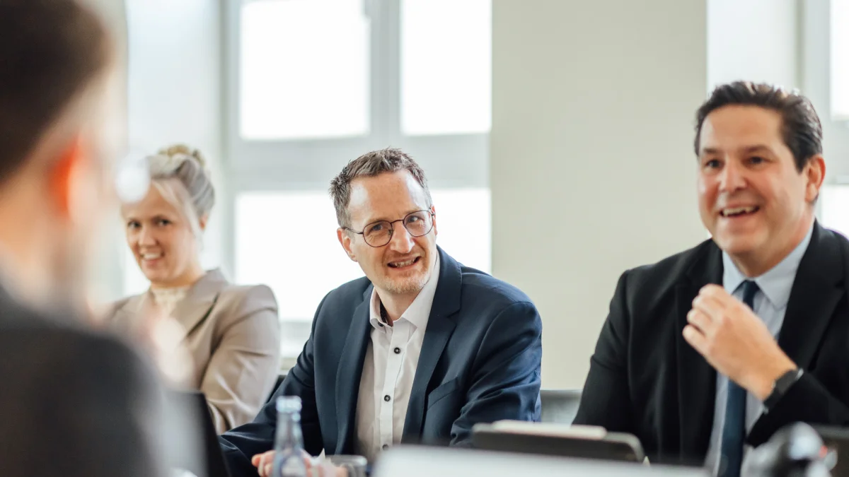 Mehrere Personen im Gespräch in einem Besprechungsraum. Das Bild steht für persönliche Beratung und Zusammenarbeit beim GVWE.