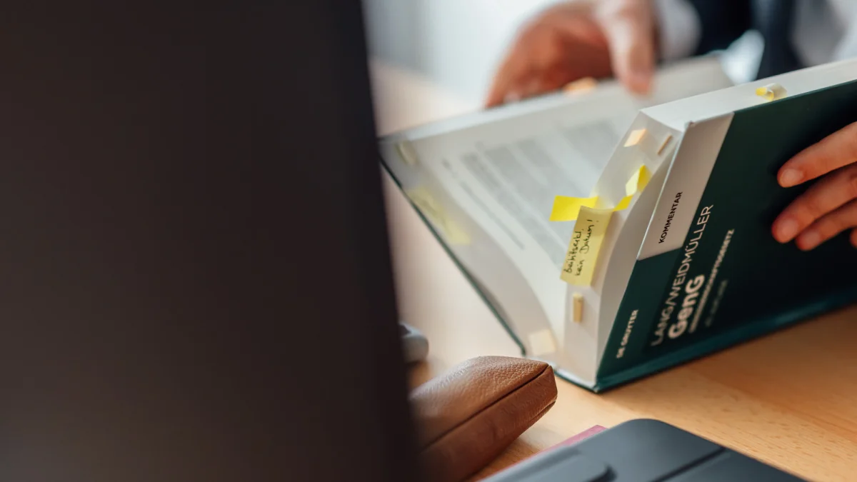 Eine Person blättert in einem markierten Kommentar zum Genossenschaftsgesetz. Das Bild steht für die fachliche Verbandsprüfung beim GVWE.